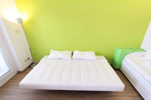 two beds in a room with a green wall at Hostdomus - Green Tech Apartment in Sestriere