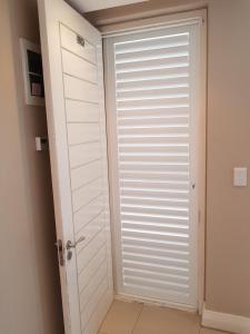 a door to a room with a white shutter at 180 Eden on the Bay, Big Bay in Big Bay