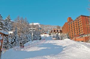 une piste de ski avec des arbres et des bâtiments enneigés dans l'établissement Azureva Les Karellis - Skipass Inclus!, à Montricher-le-Bochet