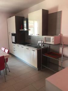 a kitchen with white cabinets and a pink microwave at La maison de Medea in Pulsano +21 photos