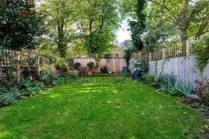 a backyard with a fence and a green yard at Veeve - East London Elegance in London