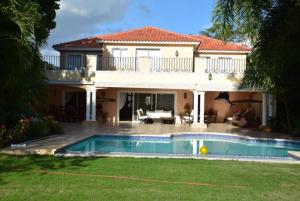una casa grande con piscina frente a ella en Metro Country Club en Juan Dolio