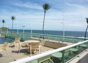 balcón con mesa, sillas y vistas al océano en Bahia Flat Apt 124 Farol da Barra, en Salvador