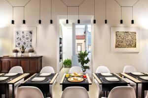 a dining room with black tables and white chairs at Artemisia Domus - Centro Storico in Naples