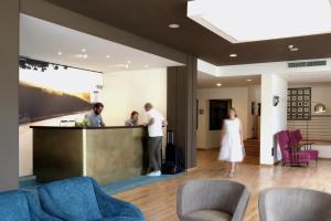 a group of people standing at a bar in a lobby at Hotel Luise in Riva del Garda