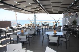 a restaurant with tables and chairs and the ocean at Meliton Inn Hotel & Suites by the beach in Neos Marmaras
