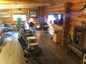 a living room with leather furniture and a log wall at Summit River Lodge & Campsites in Valemount