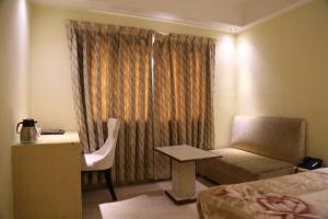 a hotel room with a bed and a desk and a chair at Mayur Hotel in New Delhi