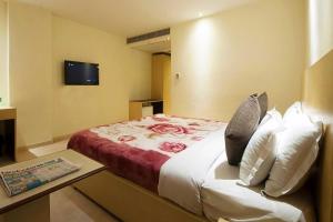 Mayur Hotel في نيودلهي: غرفة في الفندق سرير مع وسائد وتلفزيون