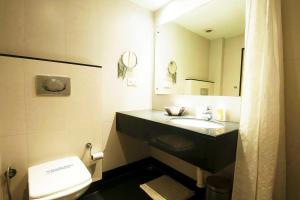 a bathroom with a toilet and a sink and a mirror at Mayur Hotel in New Delhi