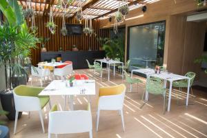 un restaurante con mesas blancas, sillas y plantas en Seen Hotel Abidjan Plateau en Abiyán