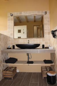 ein Bad mit einem schwarzen Waschbecken und einem Spiegel in der Unterkunft Domaine Insolite du Petit Moras in Chomérac