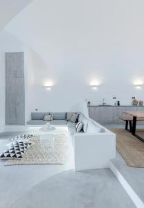 a white living room with a couch and a table at Alluvial Santorini Suites in Mesaria