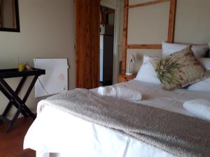 a bedroom with a white bed and a desk at The Tin Shack in Underberg