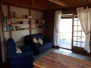 a living room with two blue chairs and a wooden table at The Tin Shack in Underberg