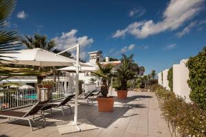 eine Terrasse mit Stühlen, einem Sonnenschirm und einem Pool in der Unterkunft Grifo Hotel Charme & SPA in Ischia