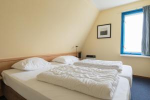 2 Betten in einem Zimmer mit weißer Bettwäsche und einem Fenster in der Unterkunft Appartement De Vrijbuiter, Resort Amelander Kaap in Hollum + 27 Fotos