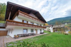 una casa con bancos y un patio de césped en Alara, en Ortisei