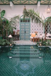 una piscina en una casa con una puerta verde en Riad BE Marrakech en Marrakech