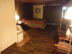 a small hotel room with a bed and a sink at Budgetel Inn & Suites Hotel in Grand Rapids