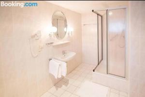 a white bathroom with a sink and a shower at Hotel Goldenes Schiff in Grimma