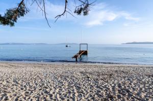 un muelle en la playa con un barco en el agua en Cap Nègre Hôtel, en Le Lavandou