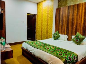 una camera da letto con un letto con una coperta verde sopra di Dwivedi Hotels Hotel Elena a Varanasi