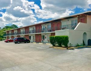 a building with a car parked in a parking lot at Red Carpet Inn Kissimmee in Kissimmee