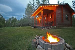una cabaña de madera con una hoguera frente a ella en Mica Mountain Lodge & Log Cabins en Tete Jaune Cache