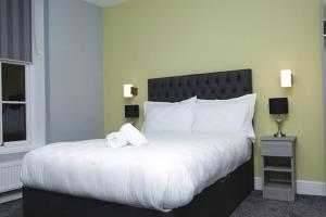 um quarto com uma cama grande com lençóis brancos e almofadas em The Spring Bank APARTHOTEL em Preston