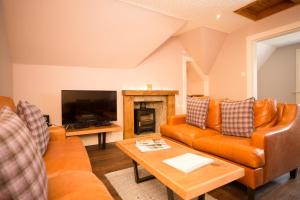 a living room with orange furniture and a fireplace at Ptarmigan in Aviemore