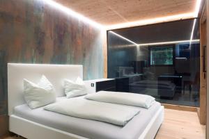 a bedroom with a white bed and a living room at Neuprantl Apartments in Lana