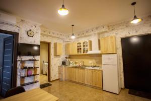 Una cocina con gabinetes de madera y un refrigerador blanco. en Apartment Art Django Old Avlabari, en Tiflis