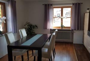 a dining room with a black table and white chairs at Am alten Skihang in Wallgau