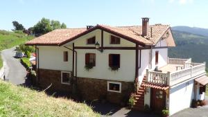 ein weißes Haus mit Balkon auf einem Hügel in der Unterkunft Agroturismo Kasa Barri in Bermeo