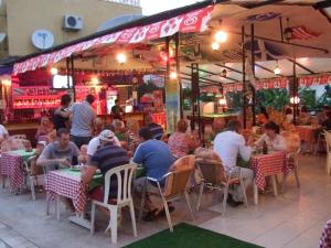 a group of people sitting at tables in a restaurant at Club Sunset Apartments in Marmaris