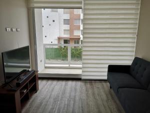 sala de estar con sofá y ventana grande en Apartamento la serena a pasos del mar, en La Serena