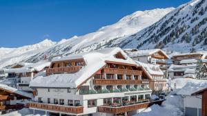 a building covered in snow with mountains in the background at Hotel Wiesental in Obergurgl