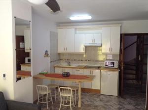 cocina con armarios blancos, mesa y sillas en Apartamentos Brisamar a 50 metros de la playa, en Valle Gran Rey