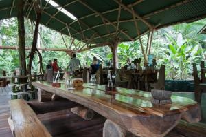 a large wooden table in a restaurant with people in the background at Danta Corcovado Lodge in Rincón