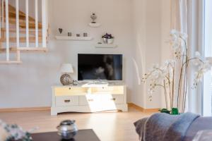 a living room with a tv on a white cabinet at Ferienwohnung Zum Kliff in Nienhagen