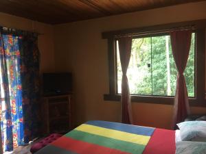 um quarto com uma cama colorida e uma janela em Loft Cravo & Canela em São Pedro da Serra