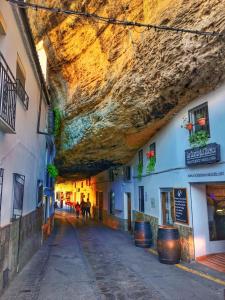 a narrow street with a large rock above it at Casa cueva de la sombra in Setenil