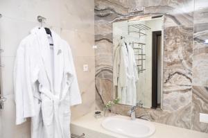 a white bathroom with a sink and a mirror at Light Hotel in Dnipro