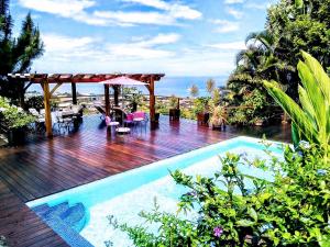 una piscina con terraza de madera y pérgola en Fare Sunny, en Punaauia