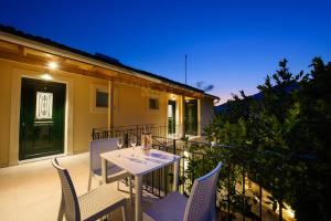 a table and chairs on a balcony at night at Dorotea Luxury Rooms in Ipsos