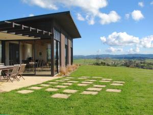 a house with a table and chairs in the grass at Te Kahu in Whangarei