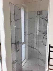 y baño con ducha y paredes de mármol. en Modern Self Contained Apartment in Riverhead en Riverhead