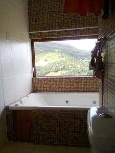 a bath tub in a bathroom with a window at Casa em Conceição de Ibitipoca in Conceição da Ibitipoca