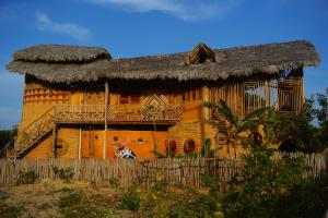 una casa antigua con techo de paja y una valla en Raízes Eco Hostel, en Barra Grande